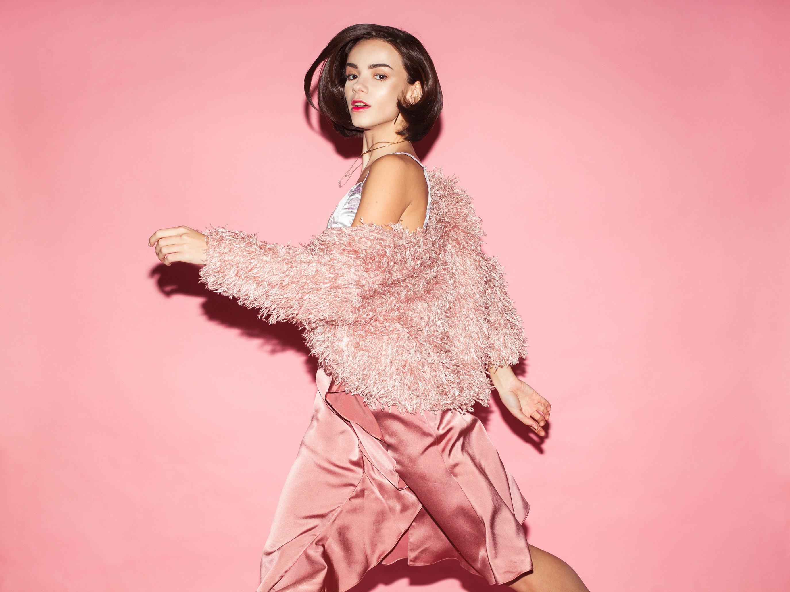 fashionable woman in pink dress on pink background